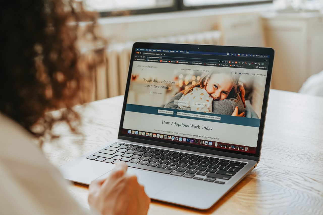 A woman researching adoption information on a laptop indoors.